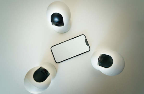 Three webcam type cameras in a triangle, all facing a phone with a blank white screen in the centre. 