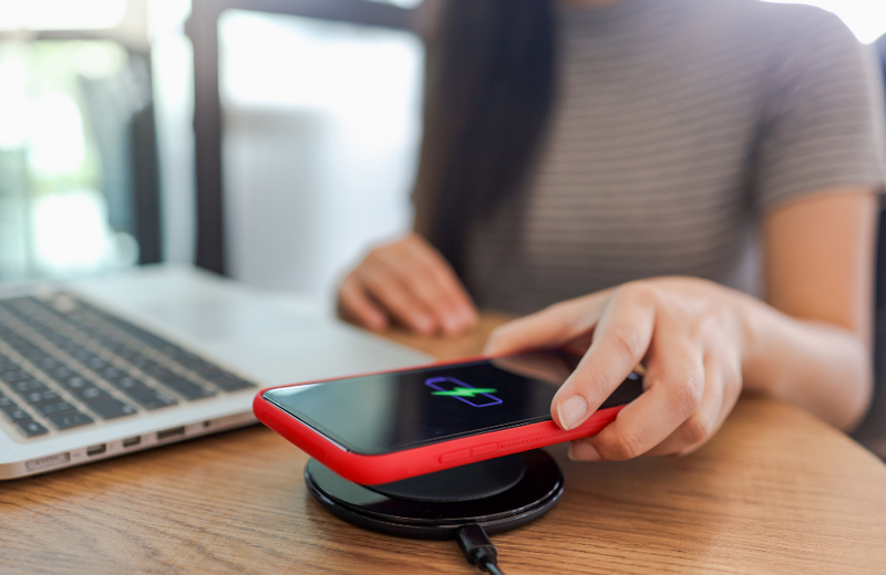 A woman placing her phone down on top of a wireless charger. 