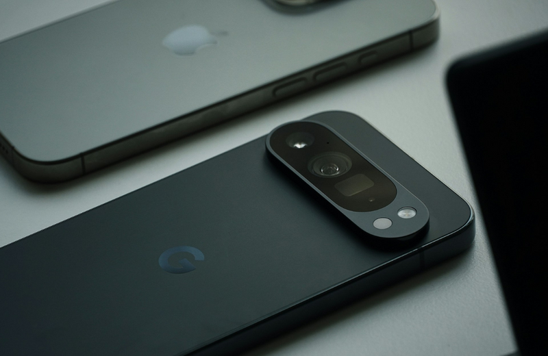 A black Google Pixel phone facedown next to a grey iPhone. 