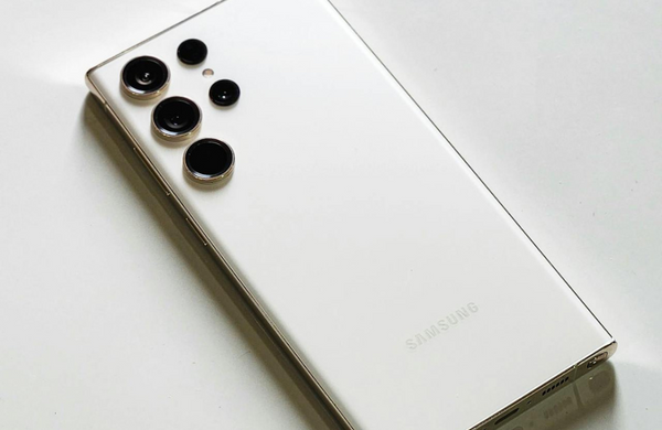 A white Samsung Galaxy S23 facedown on a white surface.