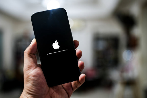 A person's hand holding an iPhone that is updating to the latest iOS.